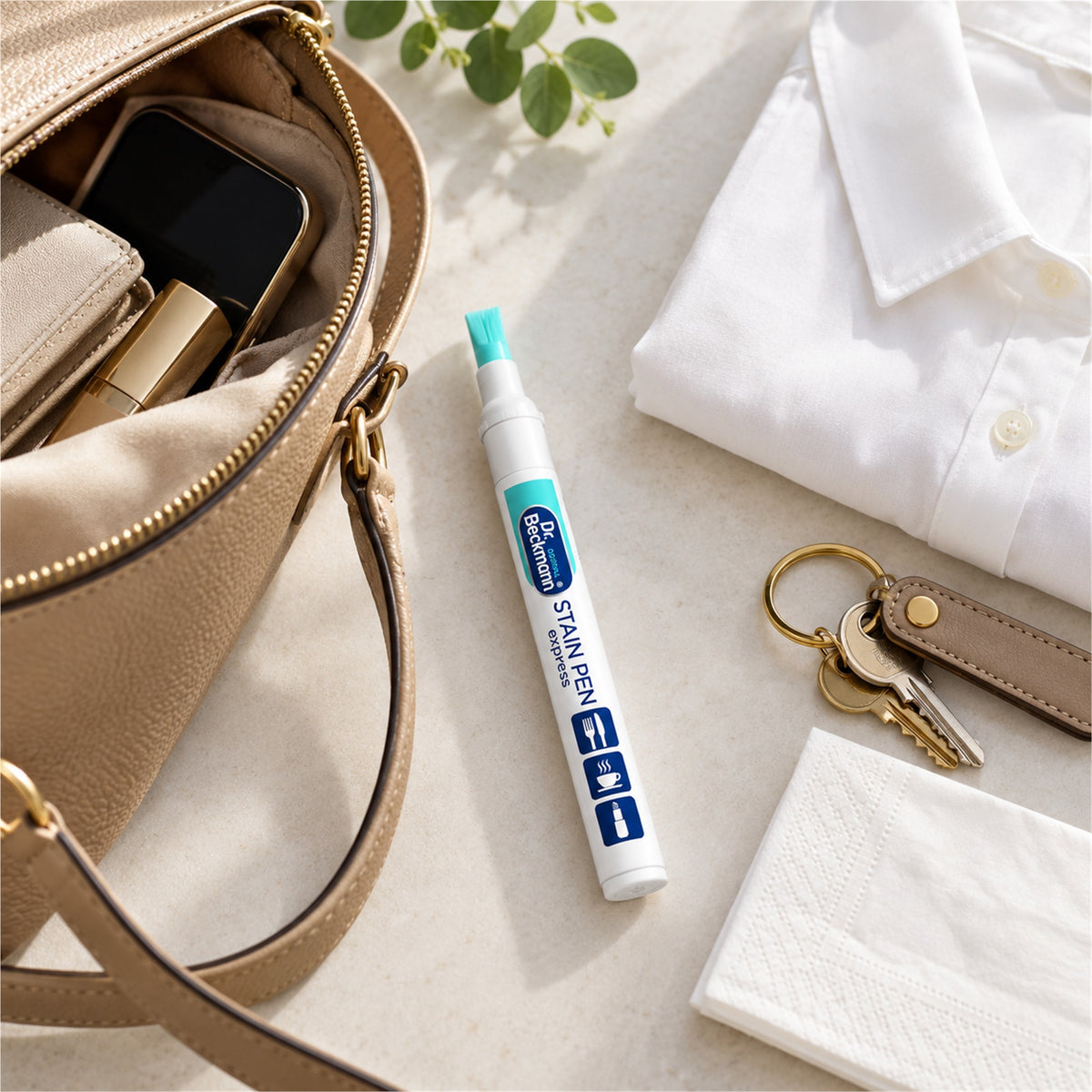 Illustrative travel flat lay with a portable Dr. Beckmann Stain Pen Express beside a handbag